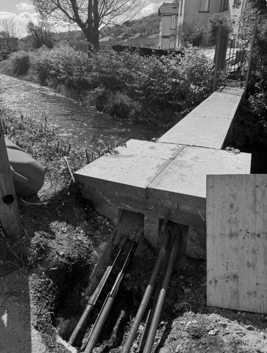 Excavated cable trench beside a watercourse where a dielectric-oil leak was treated preventively